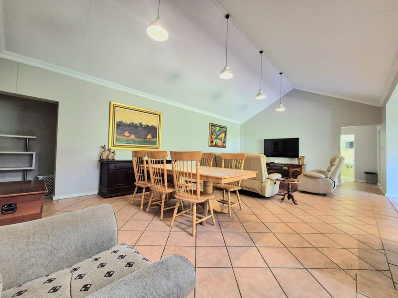 Spacious open-plan living and dining area featuring high vaulted ceilings, tiled flooring, and modern pendant lighting, creating a bright and airy atmosphere.