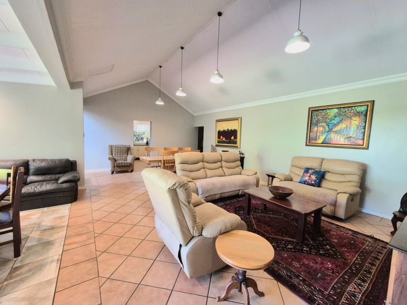 Spacious open-plan living and dining area featuring high vaulted ceilings, tiled flooring, and modern pendant lighting, creating a bright and airy atmosphere.