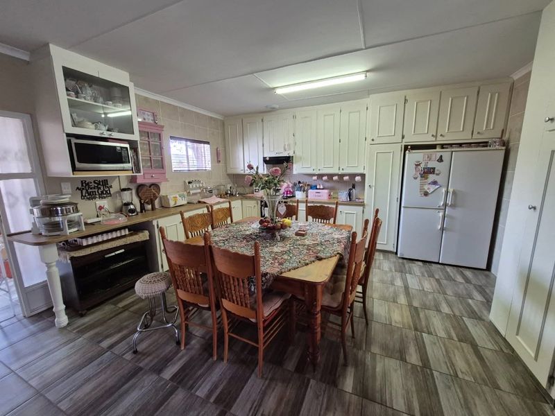 Open-plan kitchen and dining area featuring tiled flooring, ample built-in cabinetry, and integrated appliances, offering a functional space for cooking and family meals.