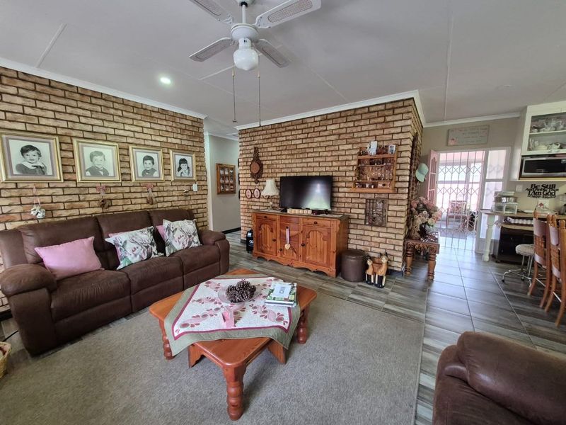 Open plan living area featuring exposed brick walls, tiled flooring, and a ceiling fan, with a view through to the entrance area.