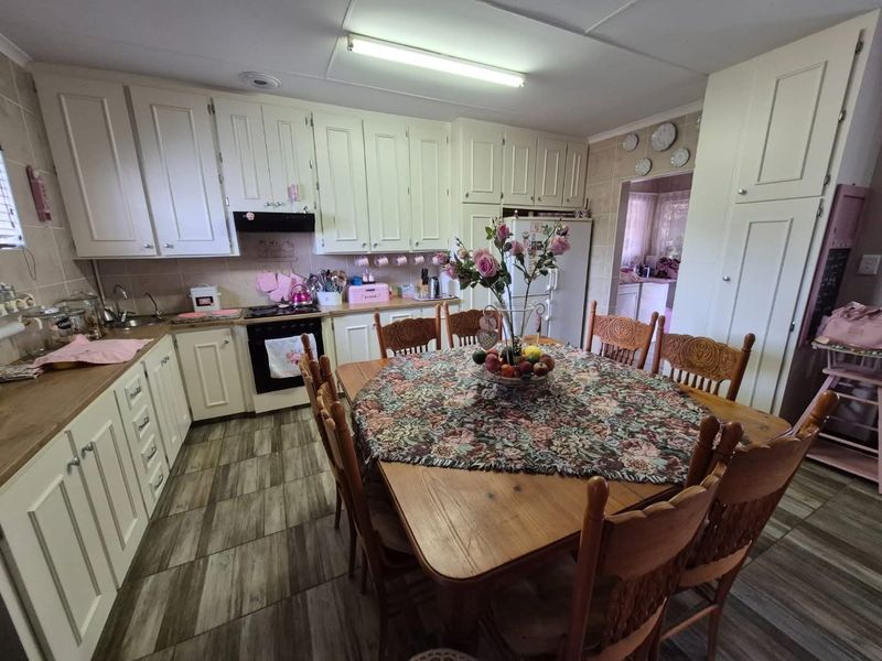 Open-plan kitchen and dining area featuring traditional cabinetry, laminate countertops, and tiled flooring, providing a functional space for cooking and family meals.