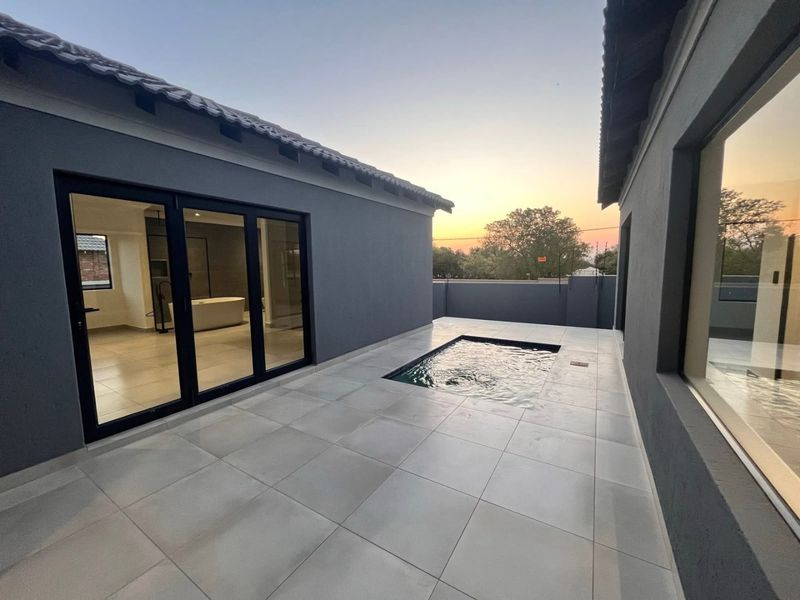 Modern townhouse courtyard featuring a sleek plunge pool, large format floor tiles, and seamless indoor-outdoor flow through expansive sliding glass doors.