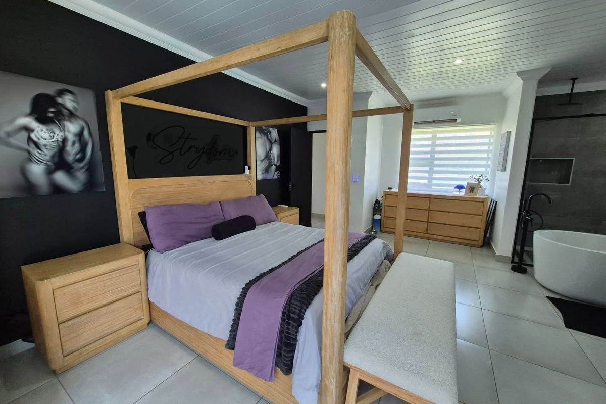 Spacious bedroom featuring tiled flooring, a tongue and groove ceiling, integrated air conditioning, and an open-plan en-suite bathroom with a freestanding tub.