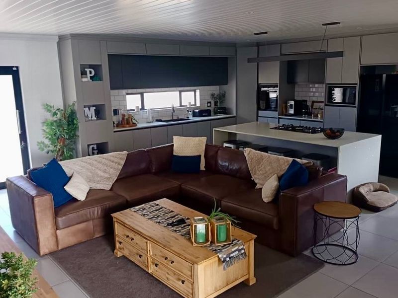 Modern open-plan living area featuring a contemporary kitchen with a central island, sleek cabinetry, and high-quality finishes throughout the space.