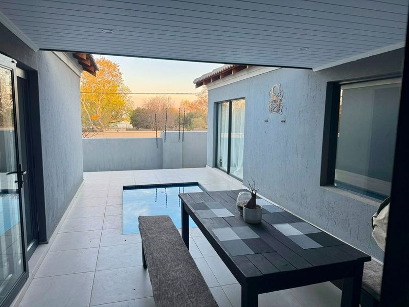 A modern covered patio featuring tiled flooring, recessed lighting, and a built-in plunge pool, seamlessly connecting to the interior living space via sliding doors.