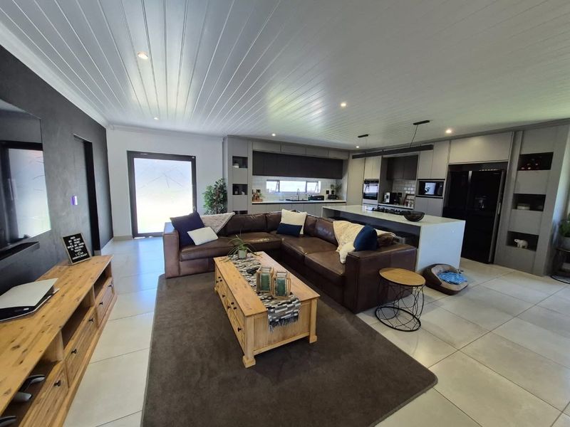 Spacious open-plan living area featuring a modern kitchen with a central island, sleek cabinetry, and integrated appliances, flowing seamlessly into the lounge space.