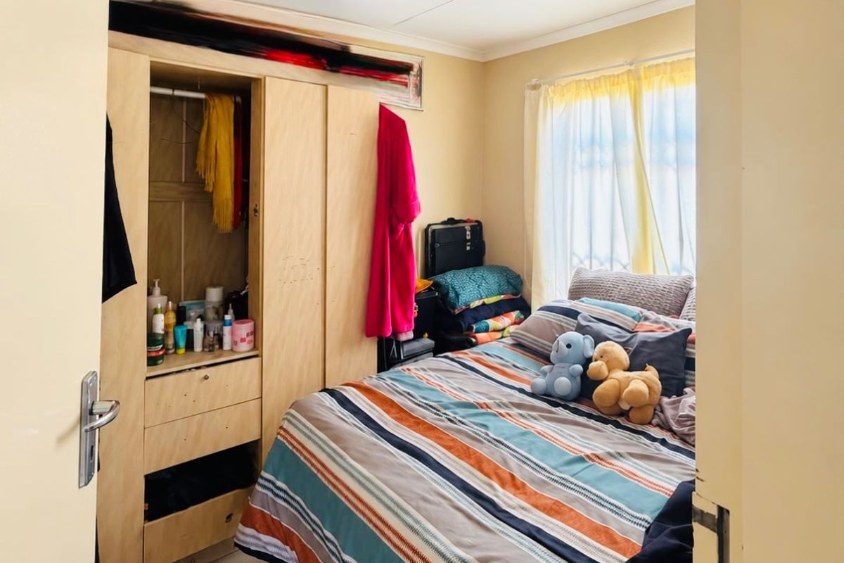 A compact bedroom featuring tiled flooring, a built-in wardrobe, and a ceiling light fixture, requiring minor cosmetic updates to improve its overall condition.