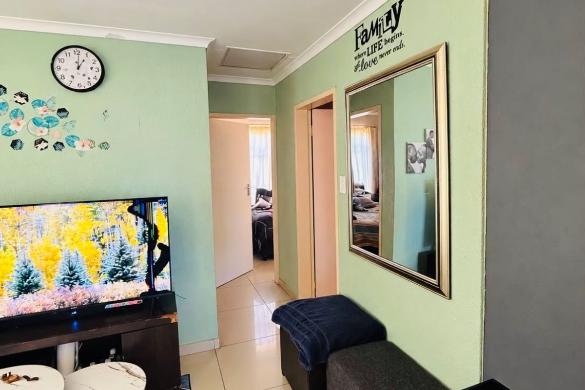 A living room area featuring tiled flooring and coved ceilings, providing a functional space with access to adjacent rooms.
