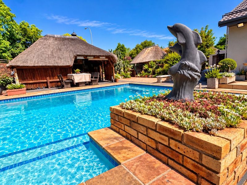 Outdoor pool area featuring a swimming pool, brick paving, and a traditional thatched lapa, providing an ideal space for outdoor entertainment.