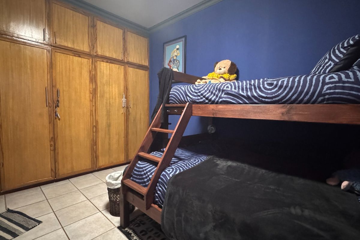 A bedroom featuring built-in wooden cupboards, tiled flooring, and crown molding, providing functional storage and a neutral base for interior updates.