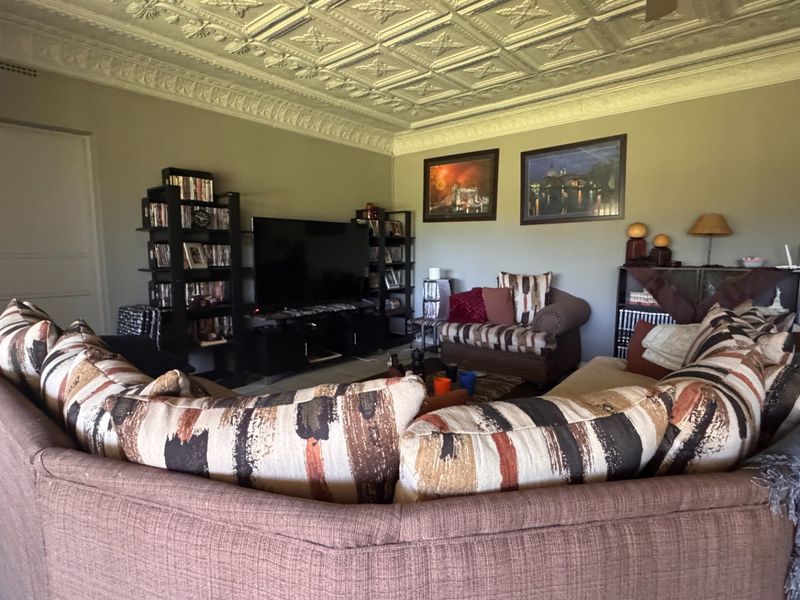 Spacious living room featuring a distinctive ornate pressed metal ceiling, decorative cornicing, and neutral wall tones, providing a classic architectural foundation.