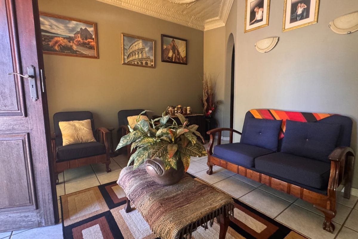 A cozy living room featuring tiled flooring, an arched doorway, and decorative ceiling cornicing, providing a classic foundation for interior updates.
