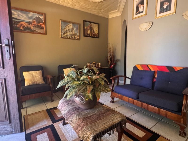 A cozy living room featuring tiled flooring, an arched doorway, and decorative ceiling cornicing, providing a classic foundation for interior updates.