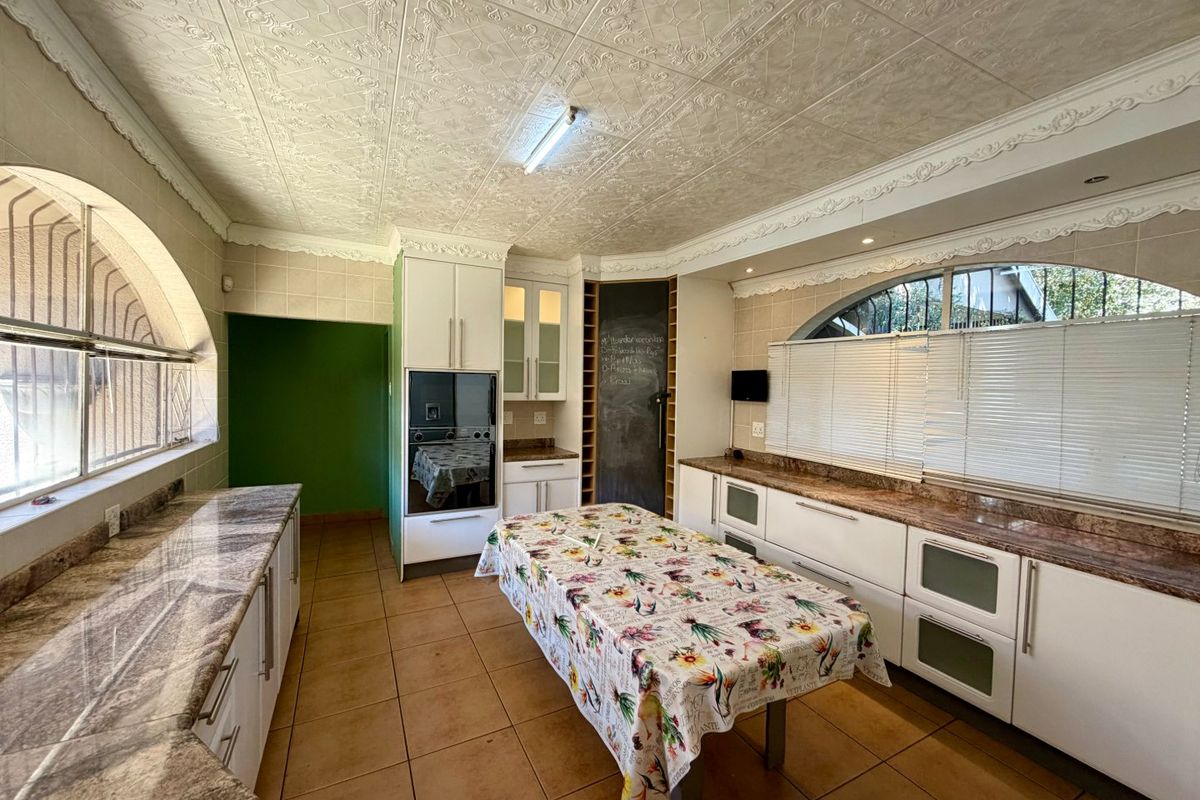 Spacious kitchen featuring granite countertops, built-in cabinetry, integrated oven, and distinctive arched windows with decorative ceiling tiles.