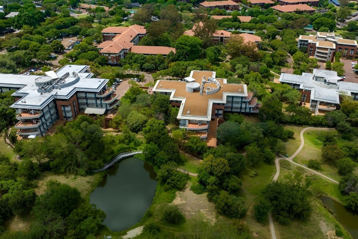 Aerial view of a commercial office park featuring multiple buildings, mature landscaping, and a central water feature.