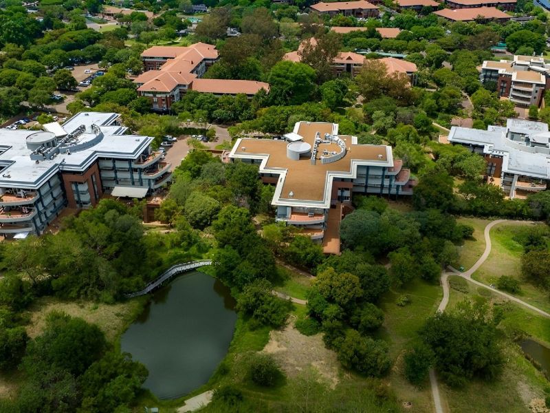 Aerial view of a commercial office park featuring multiple buildings, mature landscaping, and a central water feature.