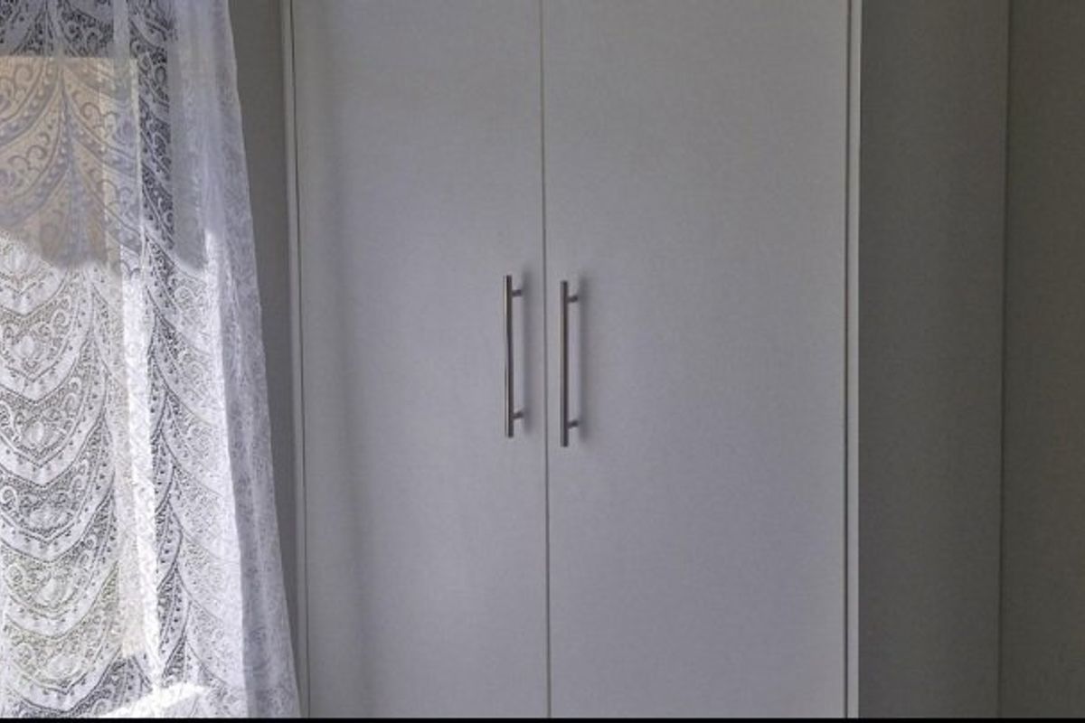 A bedroom featuring a clean, white built-in wardrobe with modern metal handles.