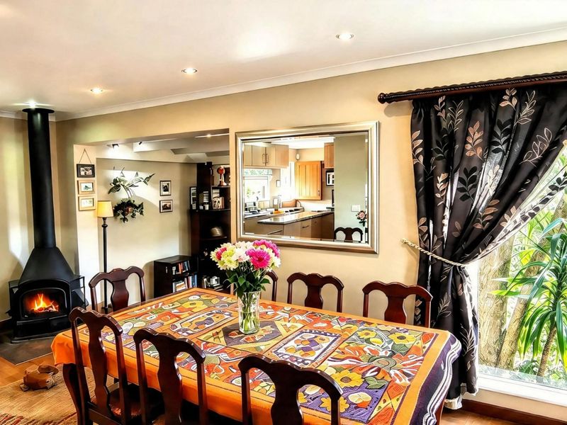 Open plan dining area featuring a cozy fireplace and views into the adjacent kitchen space, creating a warm and functional living environment.