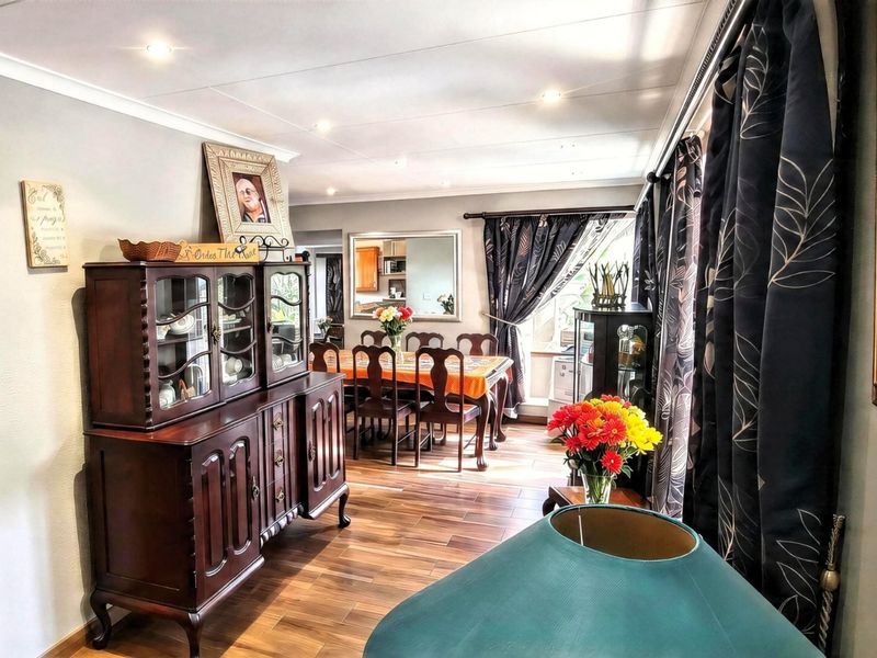 A well-maintained dining room featuring wood-look tile flooring, recessed downlighting, and a coved ceiling, creating a warm and inviting space for family meals.