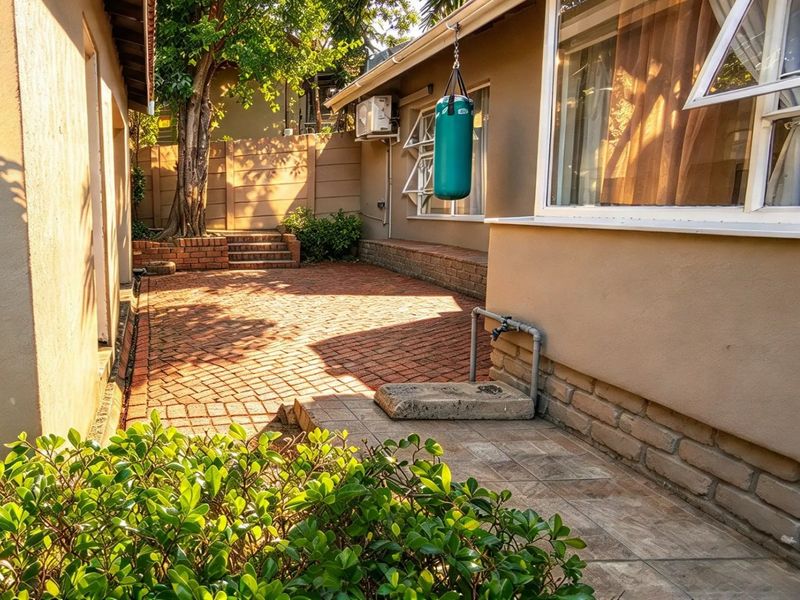 A private rear courtyard featuring brick paving, a retaining wall, and an external water tap, providing a functional outdoor space.