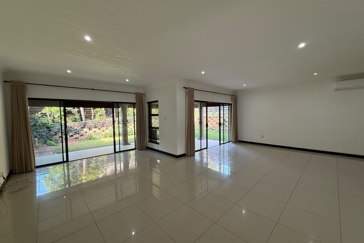 Spacious, light-filled living area featuring large sliding glass doors, polished porcelain tiles, and recessed lighting, offering seamless access to the rear garden.
