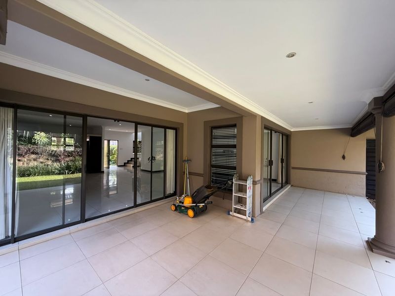A spacious covered patio featuring large sliding glass doors, tiled flooring, and recessed lighting, offering a seamless transition to the interior living space.