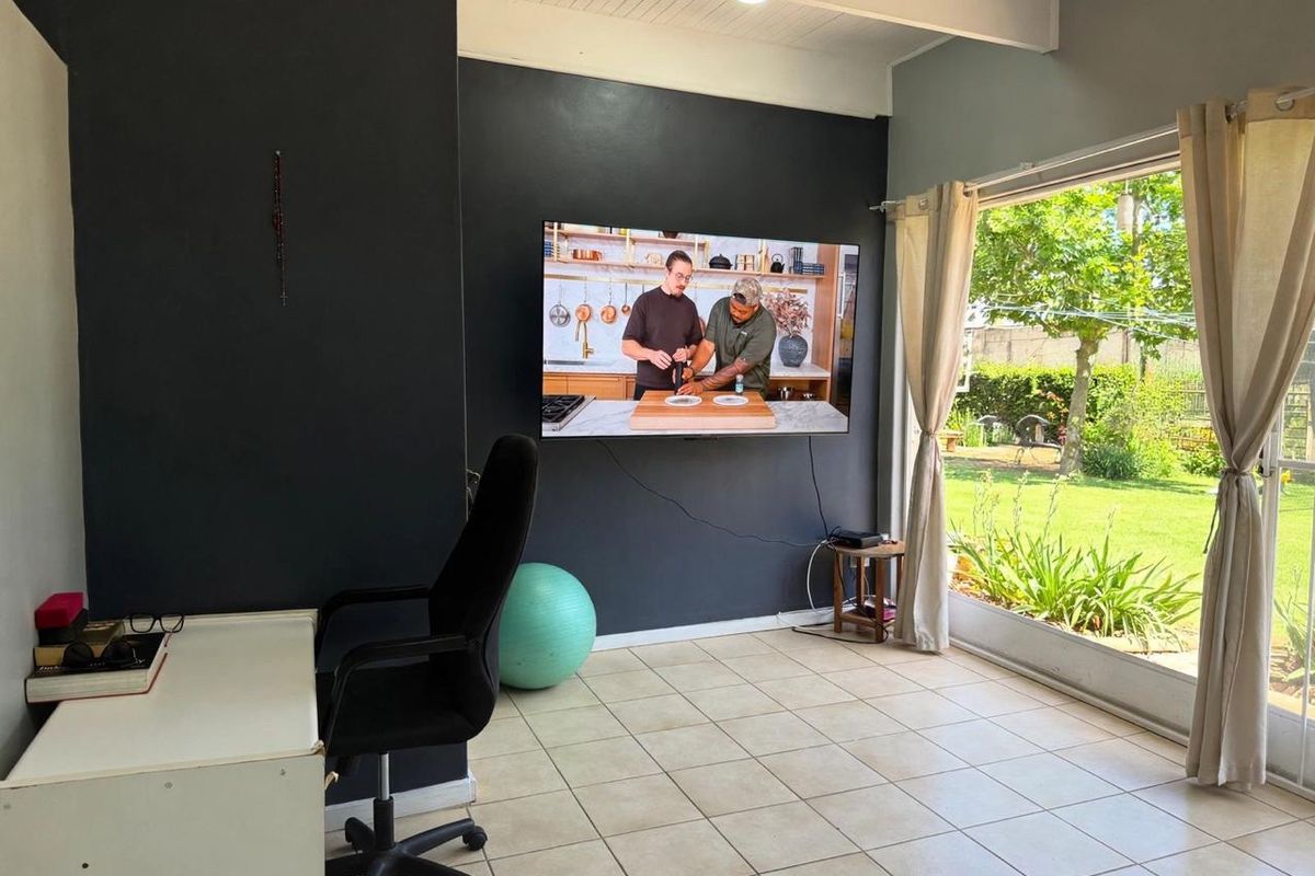 A bright living area featuring tiled flooring, a dark accent wall, and a large sliding glass door providing direct access to the garden.