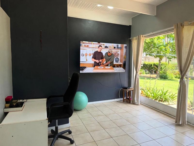 A bright living area featuring tiled flooring, a dark accent wall, and a large sliding glass door providing direct access to the garden.
