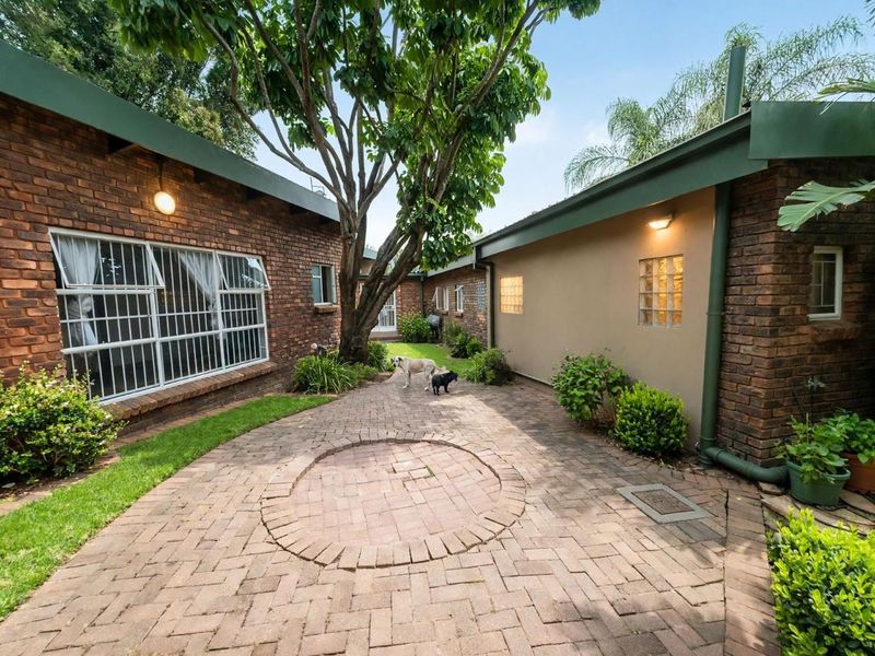 A private rear courtyard featuring brick paving, facebrick walls, and established trees, providing a quiet outdoor space.