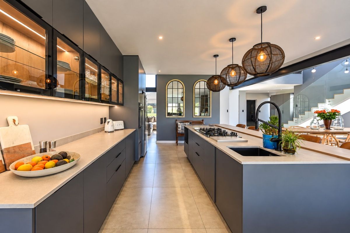 Modern kitchen featuring dark cabinetry, stone countertops, a central island with a gas hob, and elegant pendant lighting.