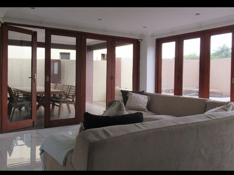 Spacious living area featuring large wooden-framed glass stacker doors that provide seamless indoor-outdoor flow to the patio and pool area.