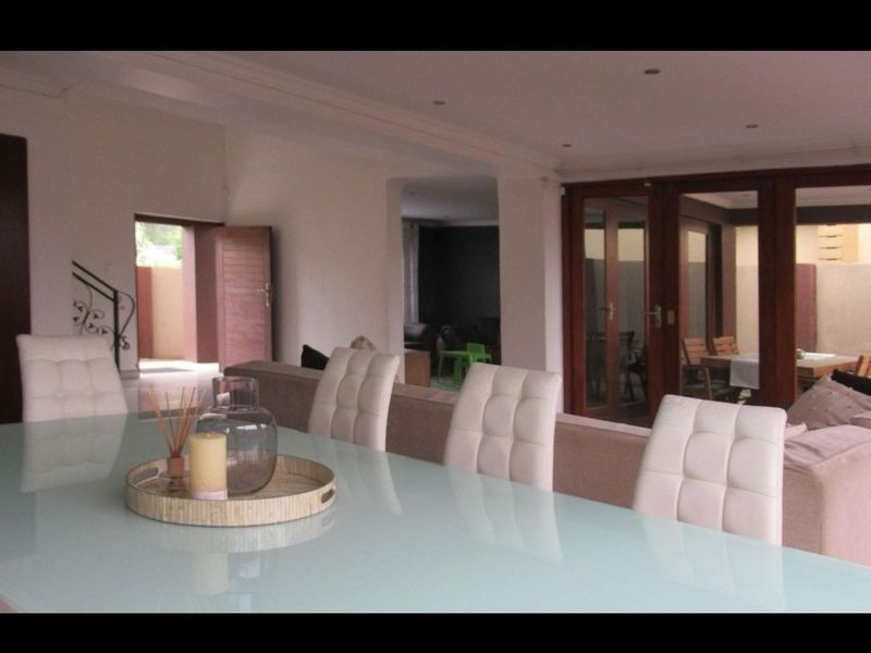 Spacious open-plan living and dining area featuring recessed lighting, large wooden-framed glass doors, and a view through to an adjacent room.