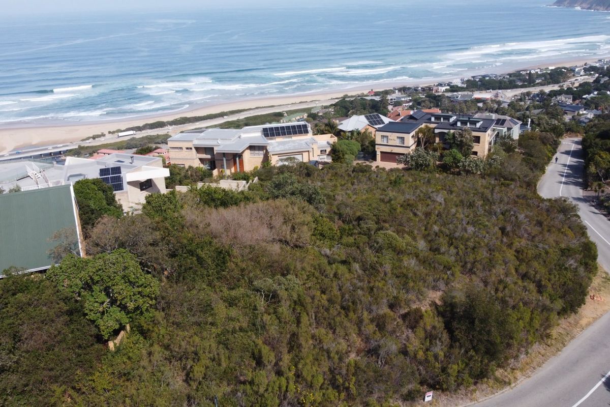 An aerial view of a vacant residential plot featuring dense coastal vegetation, situated in a prime location with proximity to the ocean.
