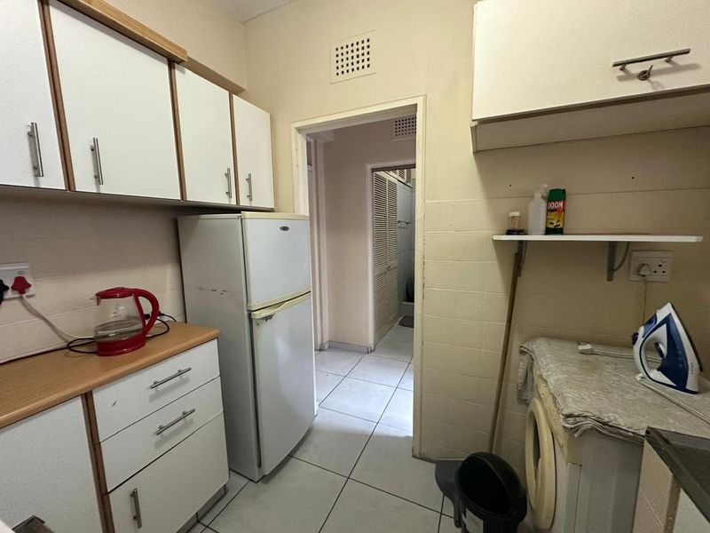 A functional laundry area featuring built-in cabinetry, tiled flooring, and dedicated plumbing connections for appliances, offering potential for modernization and improved storage efficiency.