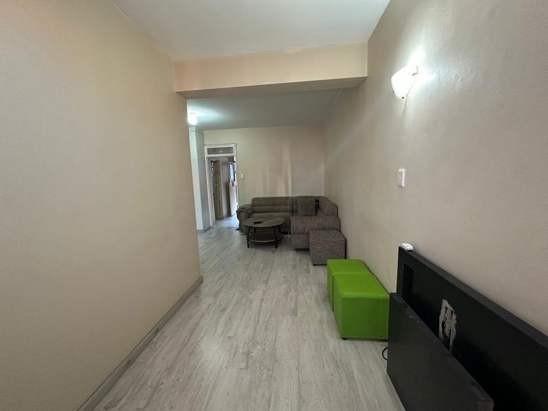 A living room area featuring light-toned laminate flooring and neutral wall finishes, providing a functional and open space.