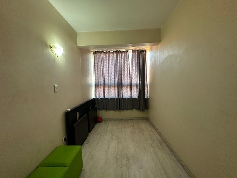 A compact, empty bedroom featuring light-toned laminate flooring and neutral walls, ready for personalization or staging.