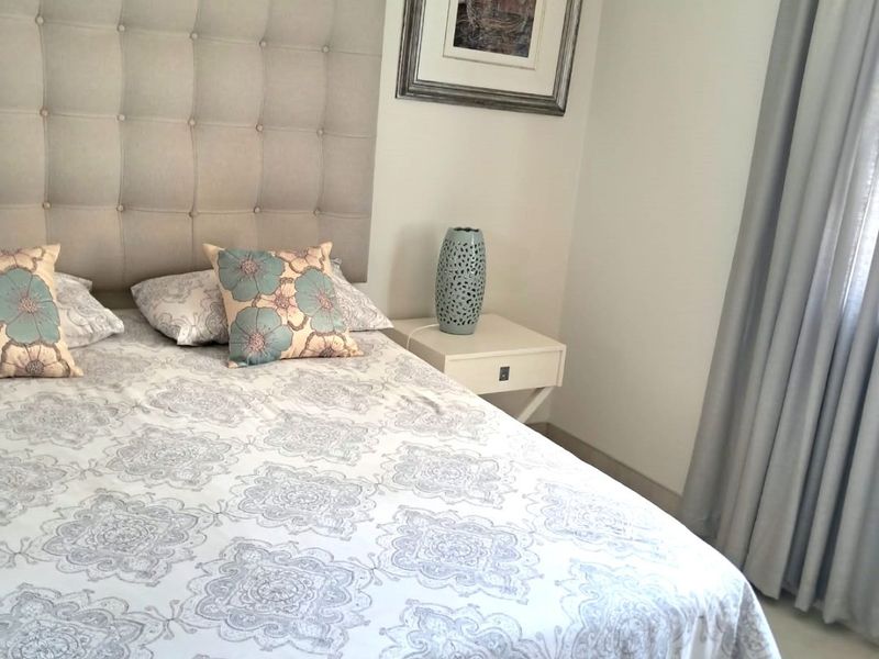 A well-maintained bedroom featuring neutral wall tones, tiled flooring, and a wall-mounted air conditioning unit.