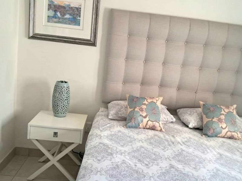 A well-maintained bedroom featuring neutral tiled flooring and a wall-mounted split-system air conditioning unit for climate control.