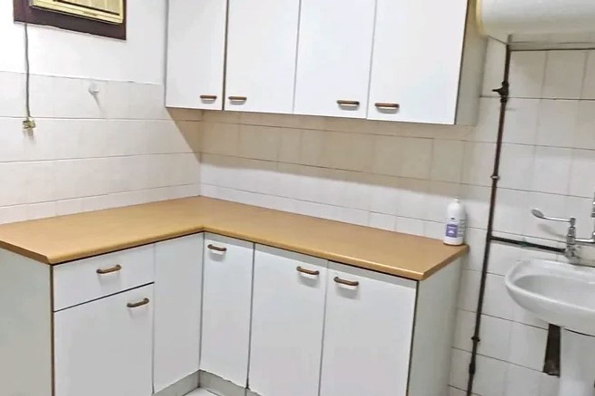 A functional scullery or utility area featuring white built-in cabinetry, a laminate countertop, and a pedestal sink with exposed plumbing.