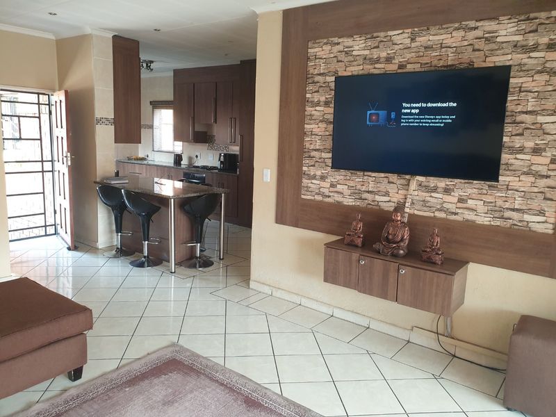 Open plan living and kitchen area featuring tiled floors, a stone feature wall, and a breakfast bar with granite countertops.