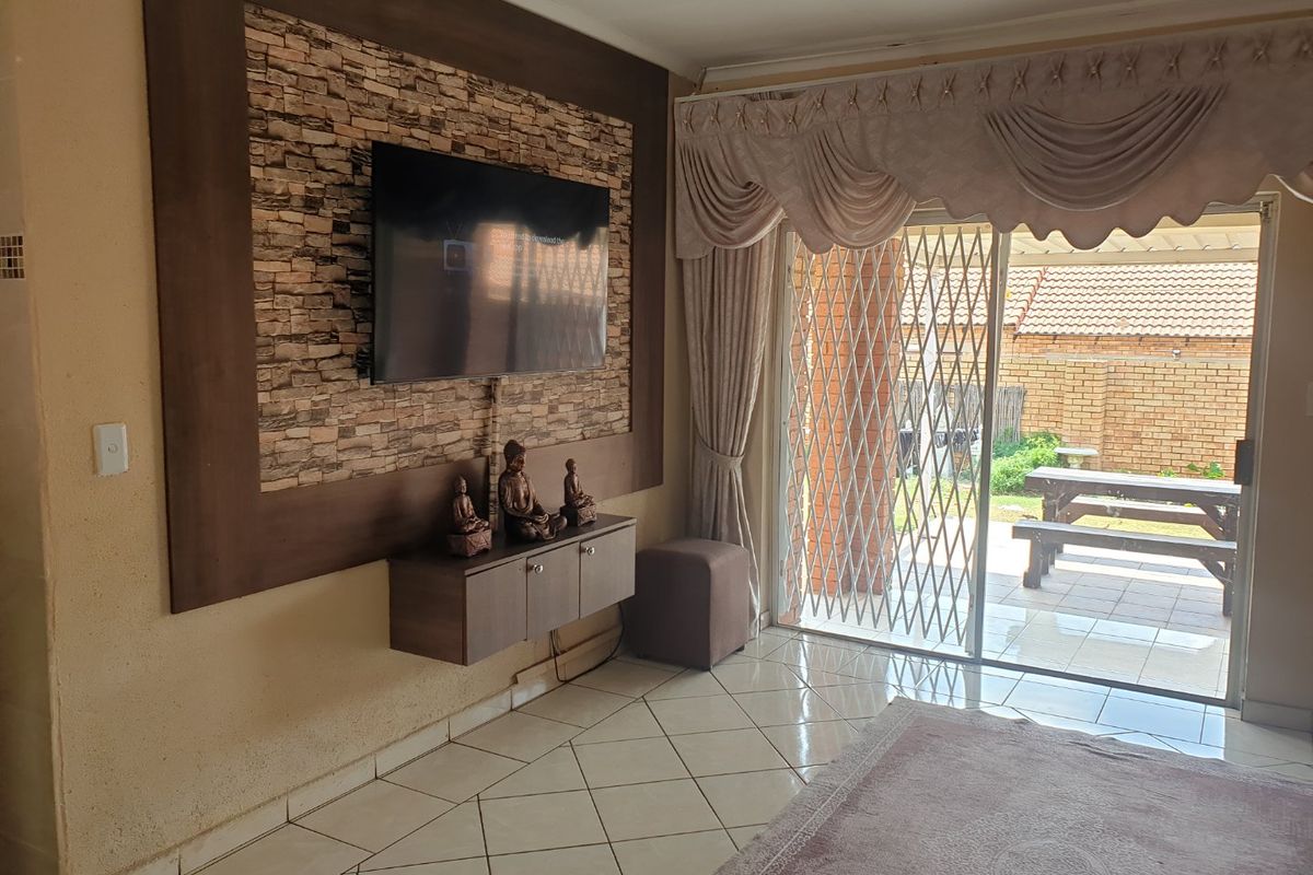 Living room featuring a stone accent wall, tiled flooring, and sliding glass doors providing access to the outdoor patio area.