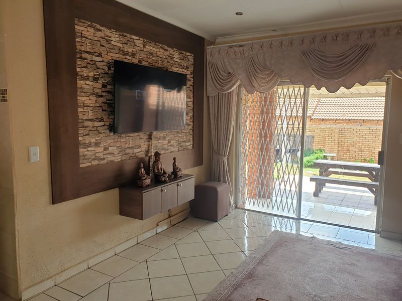 Living room featuring a stone accent wall, tiled flooring, and sliding glass doors providing access to the outdoor patio area.