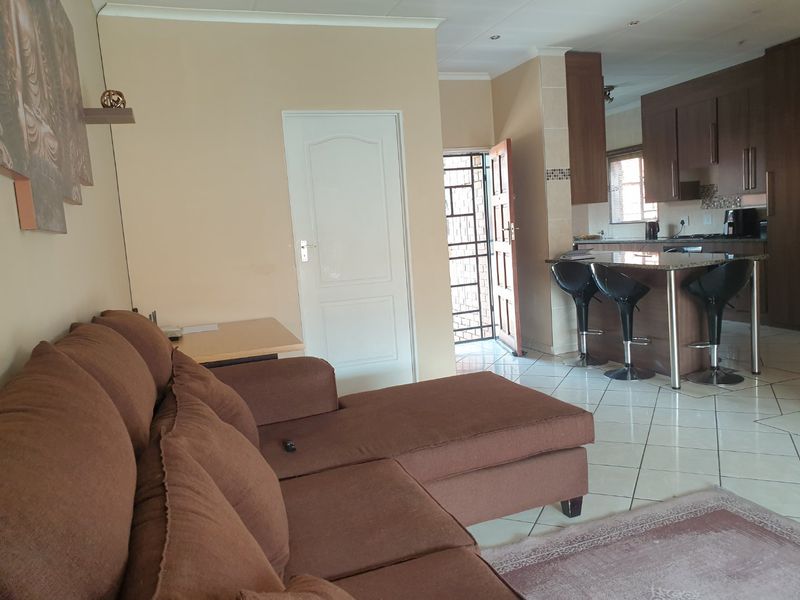 Open plan living area featuring tiled floors and a kitchen with granite countertops and dark wood cabinetry, leading to an exterior security door.