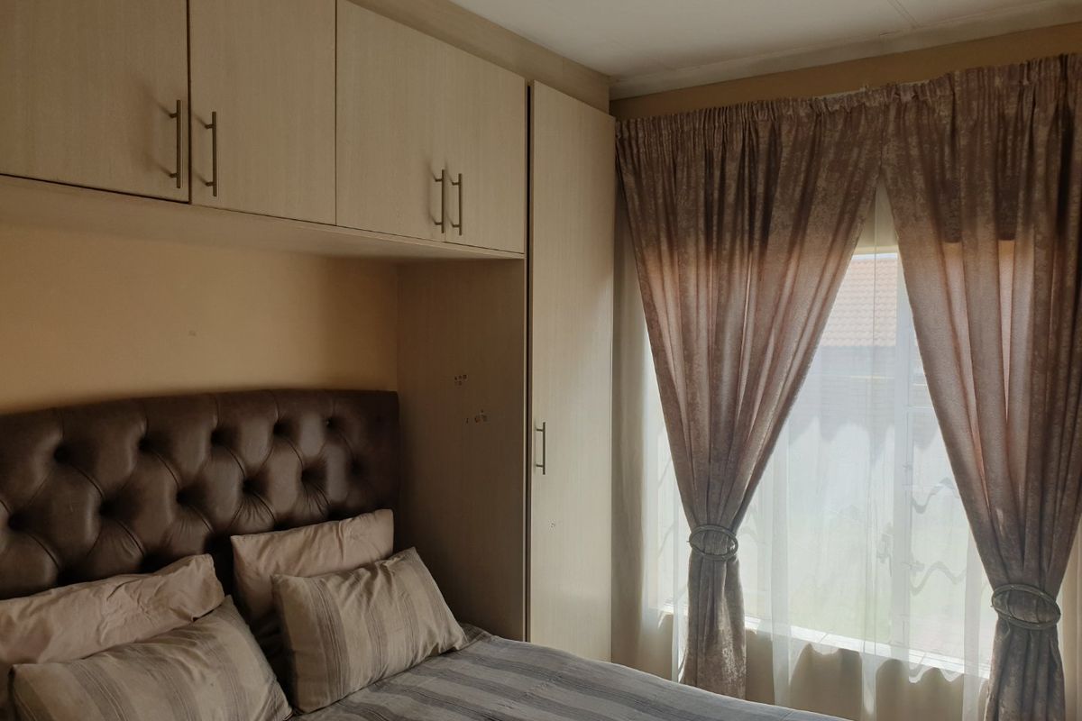 A bedroom featuring built-in cupboards and overhead storage cabinets, providing functional storage space alongside a window for natural light.