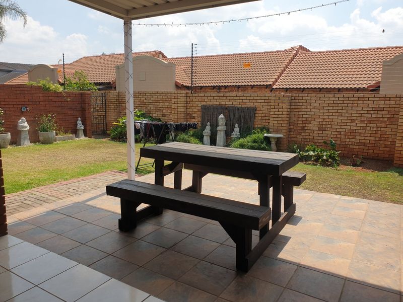 A covered outdoor patio area featuring tiled flooring and a brick boundary wall, providing a private space for outdoor relaxation.