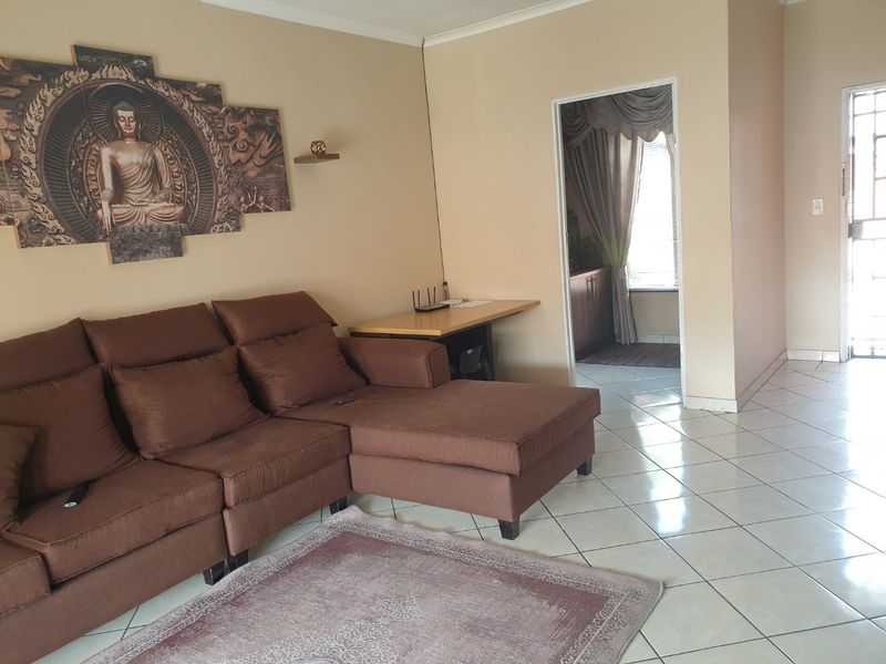 A living room featuring ceramic floor tiles and a security gate, providing access to an adjacent room.