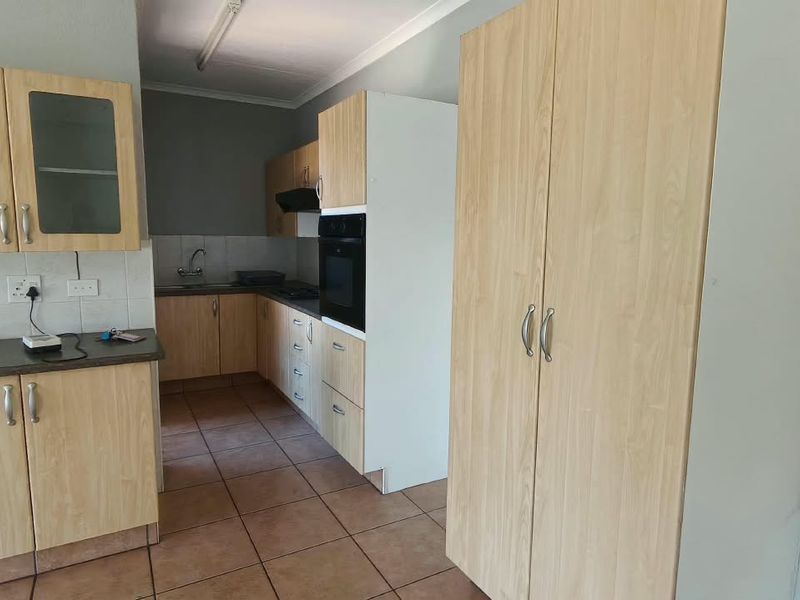 A functional kitchen featuring light wood-finish cabinetry, built-in oven, extractor fan, and tiled flooring, offering a clean and practical workspace.