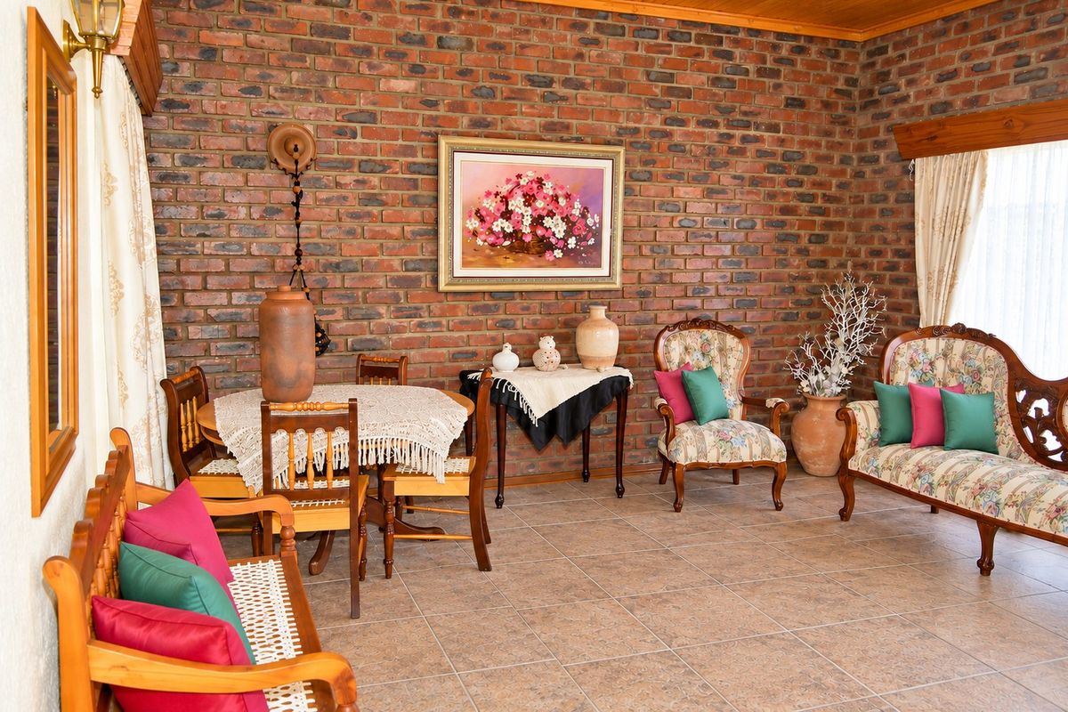 A living room featuring exposed brick walls, ceramic floor tiles, and wooden ceiling trim, offering a rustic aesthetic with potential for modern updates.