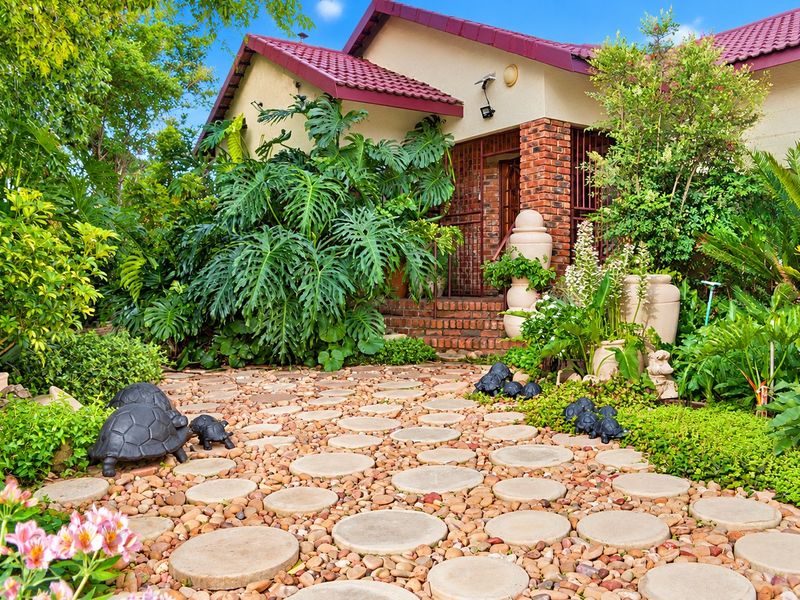A charming front entrance featuring a brick facade, tiled roof, and a well-maintained garden path leading to the home's main entry.