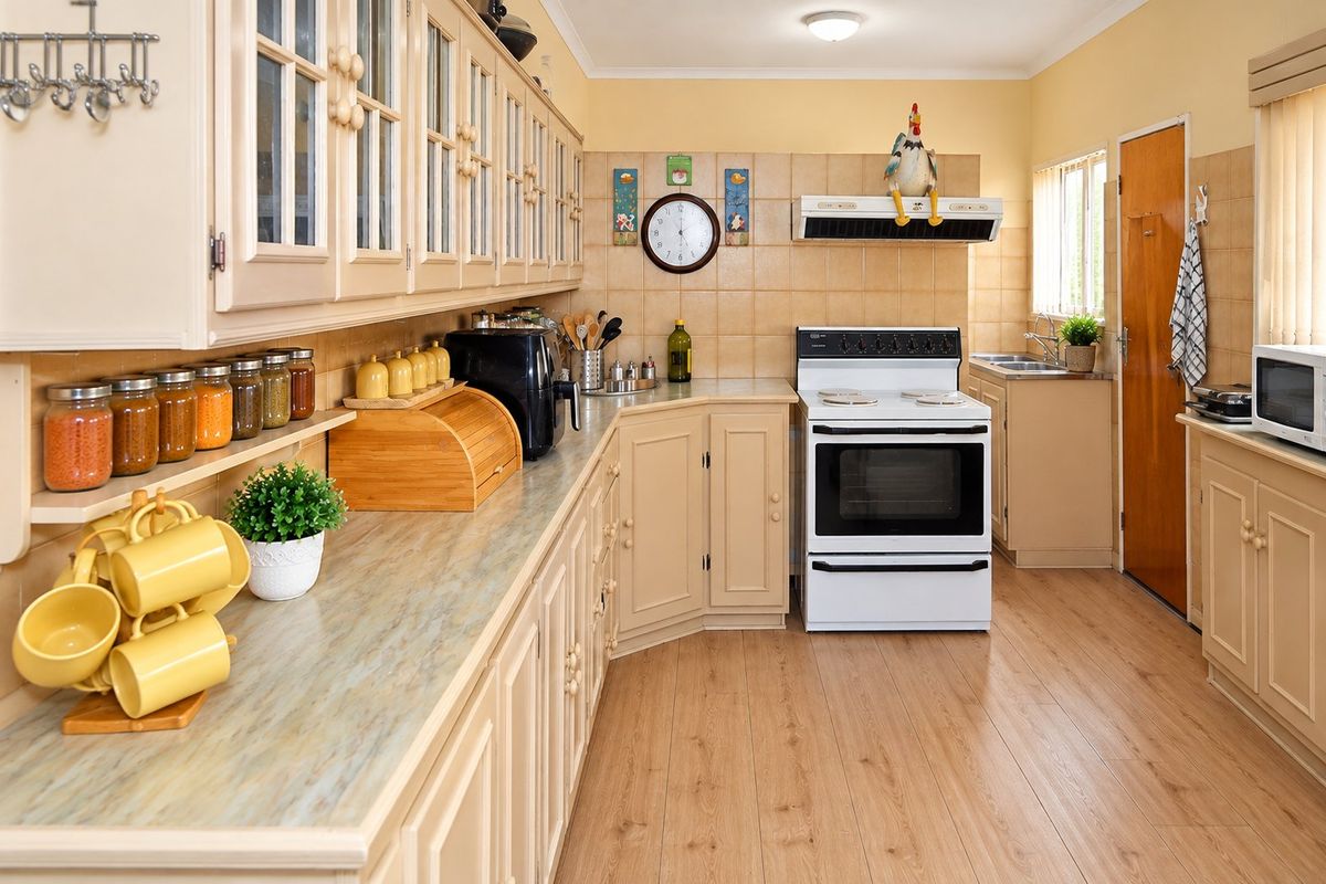 A functional kitchen featuring laminate cabinetry, tiled backsplash, and a freestanding electric stove with an extractor fan.